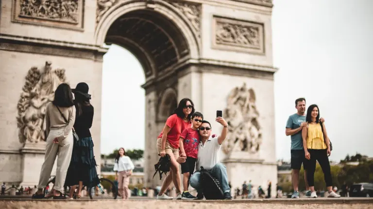 Une famille prend un selfie devant l'Arc de Triomphe à Paris en été.