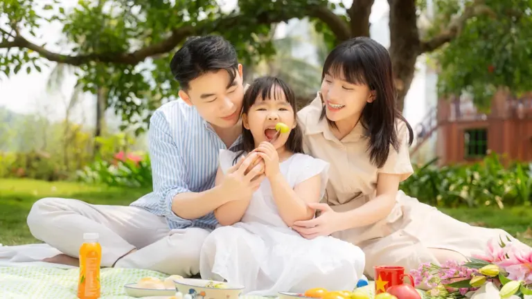 Une famille partage un pique-nique en plein air sous des arbres en été.