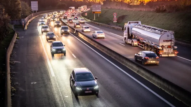 Autoroute française chargée au moment du coucher du soleil avec un trafic intense.