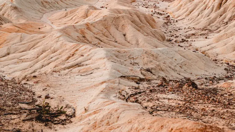 Paysage naturel de collines aux tons roses et orangés avec une terre argileuse érodée.