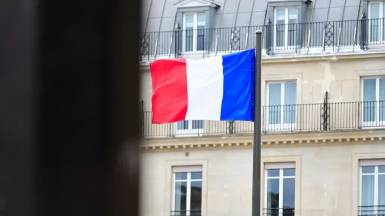 Drapeau français flottant au vent devant un bâtiment institutionnel classique