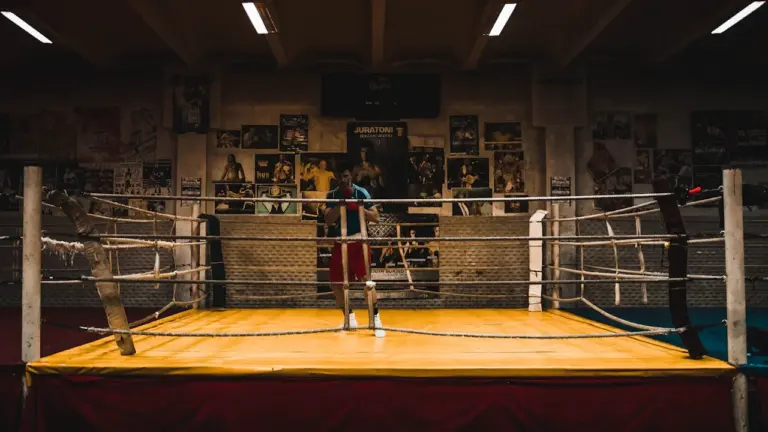 Un ring de boxe vide dans une salle d'entraînement avec des affiches au mur.