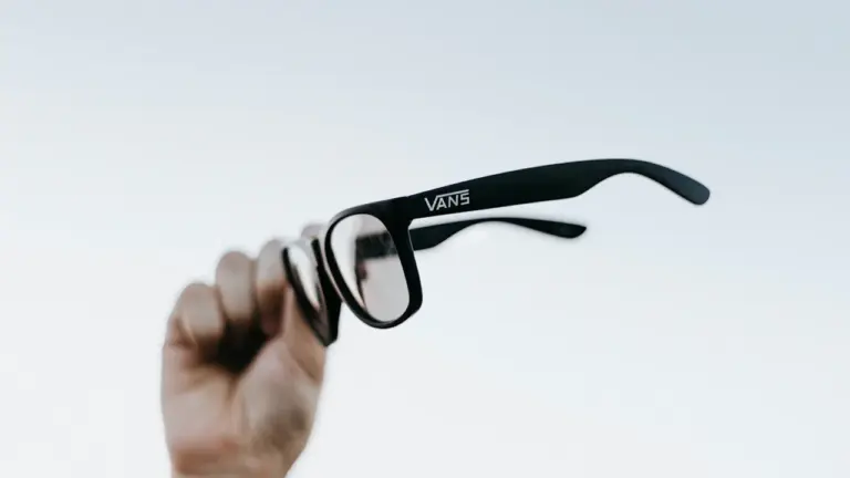 Main en l'air tenant des lunettes de protection pour observer une éclipse solaire.