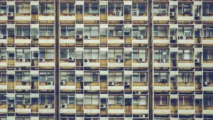 Façade d'un immeuble résidentiel avec de nombreuses unités de climatisation individuelles aux fenêtres.