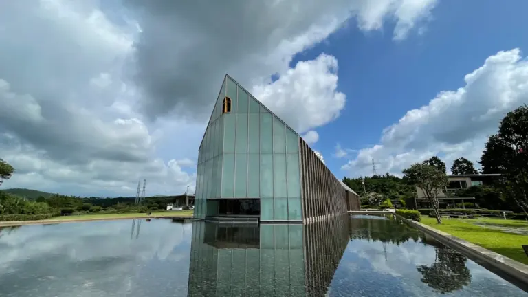 Bâtiment architectural moderne au bord de l'eau sous un ciel nuageux.