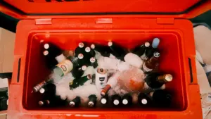 Une glacière orange remplie de bouteilles et de glace pour un pique-nique estival.