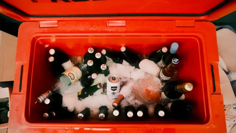 Une glacière orange remplie de bouteilles et de glace pour un pique-nique estival.
