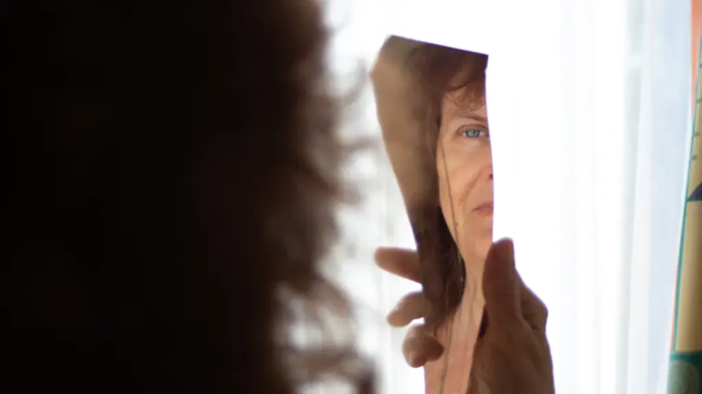 Une personne se regarde dans un miroir, reflétant une introspection sur l'image de soi.