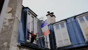 Un drapeau tricolore flottant fièrement à la fenêtre d'un bâtiment ancien en France.
