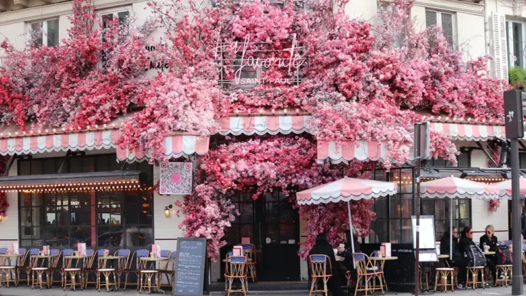 Façade fleurie d'un café typiquement parisien sur une rue animée de Paris.