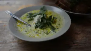 Bol de soupe verte froide sur une table en bois rustique avec une cuillère.