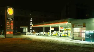 Une station-service Shell illuminée de nuit sous la neige en hiver.