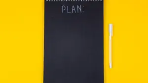 Un carnet de notes noir avec l'inscription plan sur un fond jaune vif.