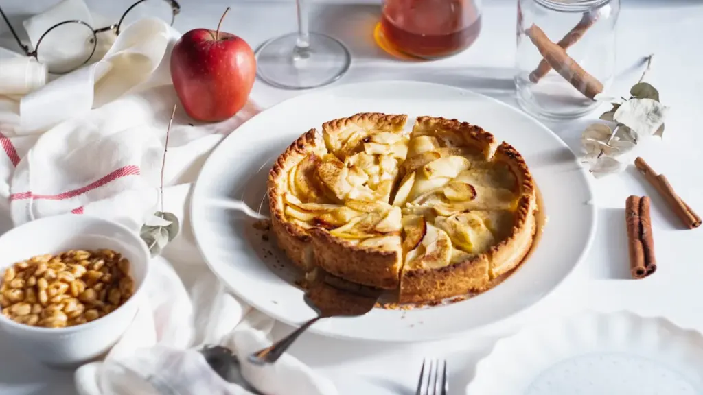Une tarte aux pommes maison avec des noisettes sur une table décorée.