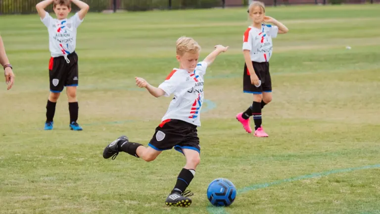 Jeunes joueurs de football sur un terrain, illustrant la formation des jeunes talents locaux.