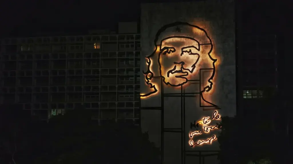 Mural monumental illuminé représentant Che Guevara sur la façade d'un immeuble la nuit.
